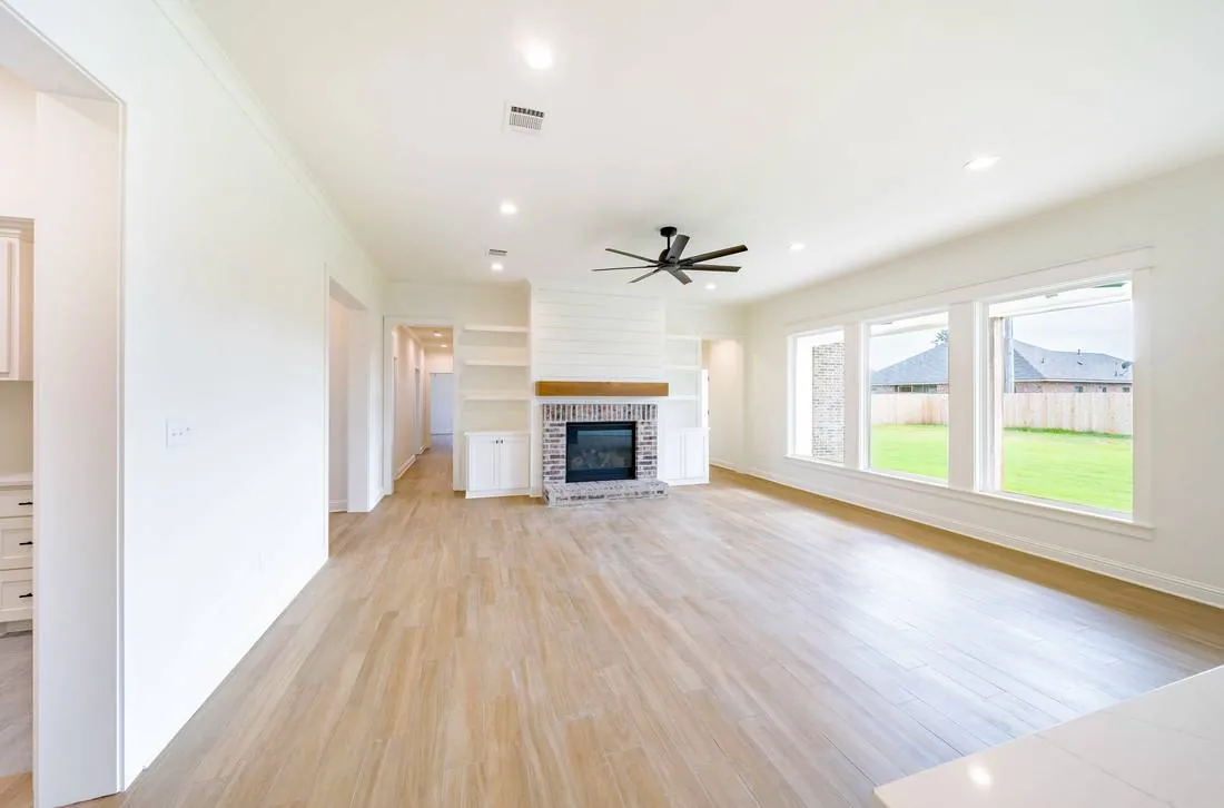 Renovated open-concept living room with exposed beams by J2 Construction